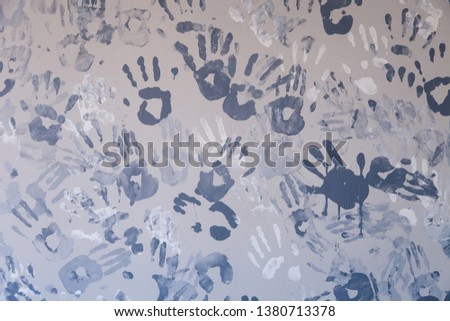 Closeup picture of many of children's handprints painted on a gray wall. Textural background. Concept wall of memory in kindergarten, school