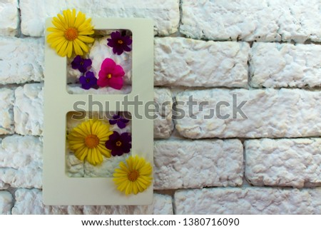 
Photo frame and summer flowers in the interior against a white wall of kerpich,Live picture with flowers or vertical juicy garden framed on the wall,Copy space