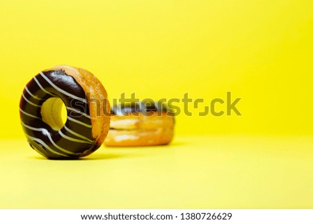 black chocolate donuts on yellow  background and space for your text. Sweet dessert