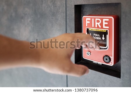 Hand try to pull down for activate fire alarm system at the wall. The hand of man is pulling fire alarm on the wall . Concept warning and alert fire alarm building. Safe and protection, emergency call