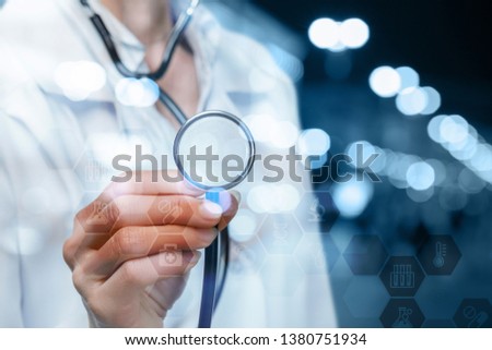 A closeup of doctor standing and touching a medical icons combs system with symbols with her stethoscope at the blurred background. The concept of compound social medical service system.