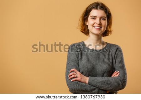 Portrait of beautiful cheerful redhead girl with flying curly hair smiling laughing looking at camera over yellow background.