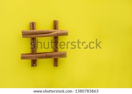cinnamon sticks isolated on yellow background. hashtag shaped sticks. Royalty-Free Stock Photo #1380783863