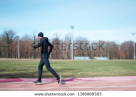 Image of athlete male running through stadium during spring jog .
