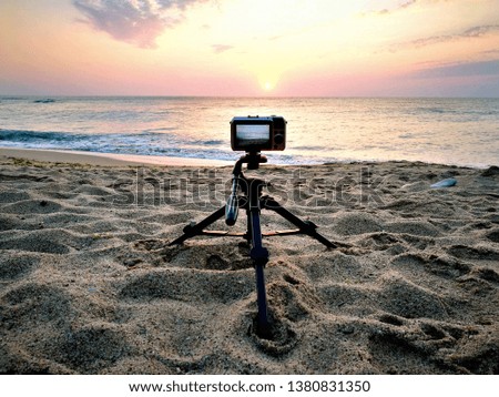 camera on tripod on sandy beach in summer during sunrise, taking sunrise photography traveling southern seas, photo camera on tripod, camera on stand, sunrise photography