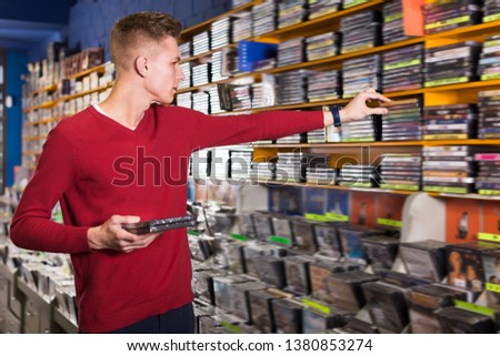 Adult man looking for interesting movies on shelves of CD shop