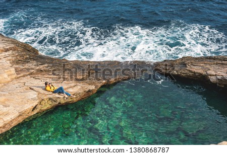 girl on a rock at the sea taking pictures