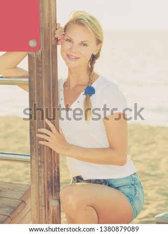 Young sport woman in white T-shirt is resting after training on the beach