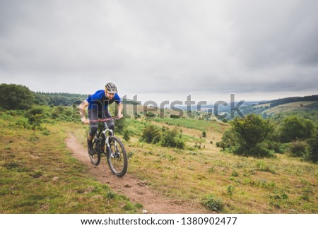 Mountain biker pushing hard up climb in English hills