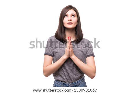 Portrait of pleading concerned young woman in light clothes holding hands together, praying isolated on white wall background in studio.