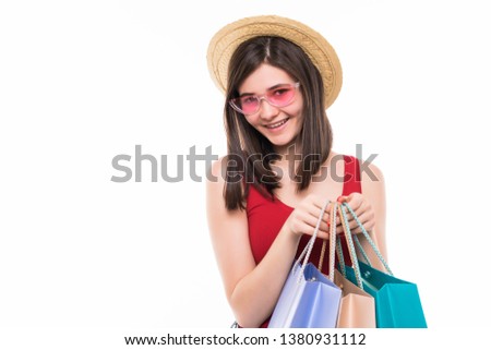 Portrait of cheerful young woman in summer hat and sunglasses holding shopping bags isolated over white background