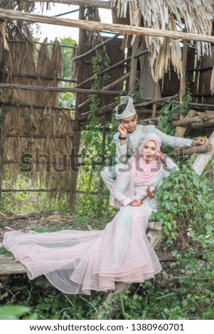 Beautiful  bride and groom  in Malay traditional cloth  on the background of old hut.