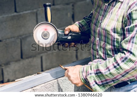 Close up on man using grinder to cut metal bar at the construction site