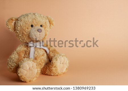 Soft warm cute brown teddy bear on color background. Isolated. Soft coral, yellow, brown background. Copy space for text.