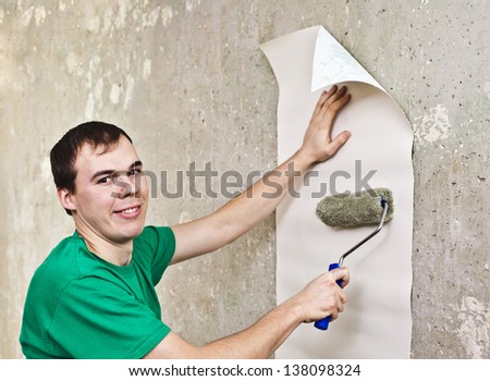 young guy misses a brush glue on the white side wallpaper