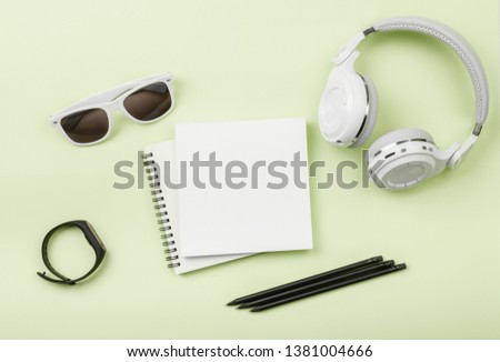 Top view mock up with phone, Fitness tracker, headphones, glasses, notebook on green background. Copy space. 'To do' list. Planning of walk route, to-do list or shopping. Smart Band Sport bracelet app