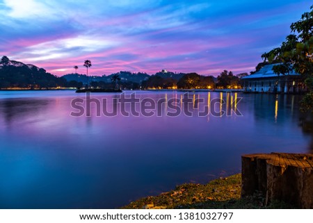 Bogambara Lake. Colorful sunset over the Kandy Lake with silhouettes of palm trees and hills on the background. Kandy, Sri Lanka