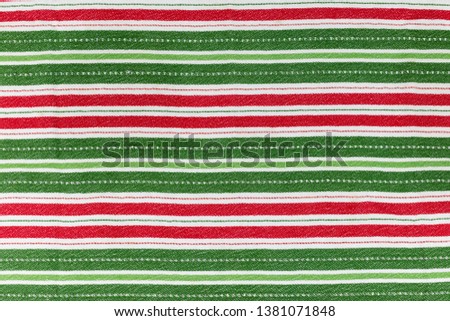 Red, white and green striped christmas tea towel/cloth flay lay. Creating a background of cloth textured festive stripes horizontally