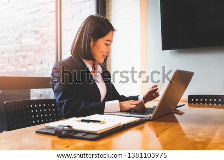 Young asian woman holding credit card and using laptop computer for purchase product on internet in home office. Online shopping concept.