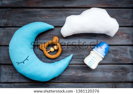 Moon pillow, clouds, baby bottle and toys for put newborn in bed on wooden background top view