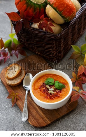 Bowl of pumpkin soup on concrete background