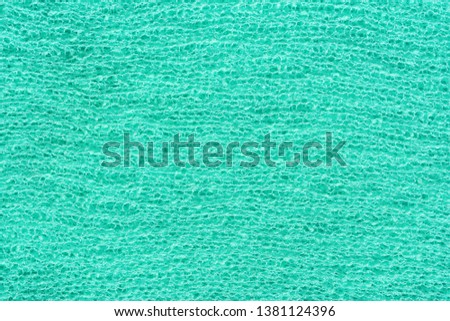 Texture of knitted fabric in aqua color. Knitted abstract background turquoise. Bright green sea fabric.