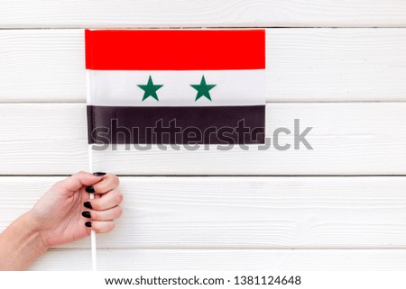 Independence Day of Syria concept with flag in hand on white wooden background top view