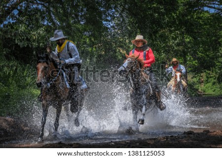 Pictures of many men wearing cowboy clothes, riding horses and traveling across the river