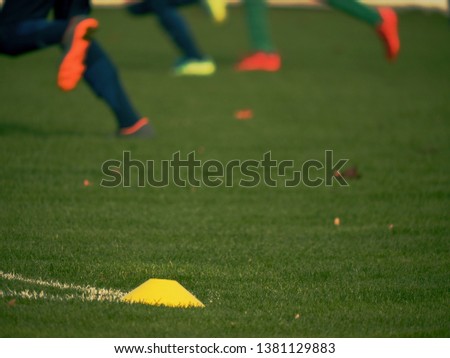 Yellow training cone. Soccer training equipment on green grass field