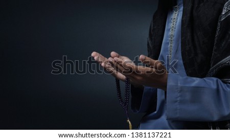 Muslim man praying isolated in black background.                          Royalty-Free Stock Photo #1381137221