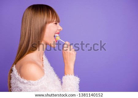 Porfile side view photo nice cute pretty teen teenager hold hand yellow lolipop trendy laughter rejoice content candid positive cheerful satisfied wear modern pullover isolated purple background
