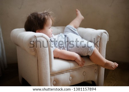 baby 11 months funny sitting on a child seat, pastel colors, gray, beige Royalty-Free Stock Photo #1381157894
