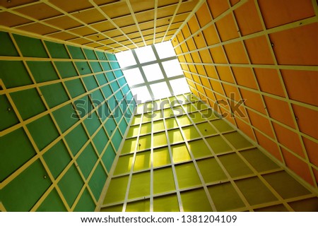 Abstract perspective of vertical lobby ceiling with skylight and strong geometry and symmetry and dramatic colours as background with space for copy