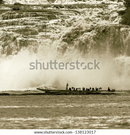 Tourists take pictures of powerful falls with tourists boat in the lagoon of Canaima national park - Venezuela, Latin America (stylized retro)