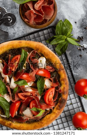 Baked pizza with ham and vegetables on grey marble tabletop with ingredients– stock image