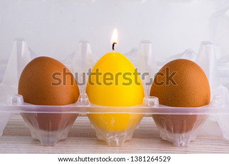 alternative concept: yellow candle eggs next to simple chicken eggs