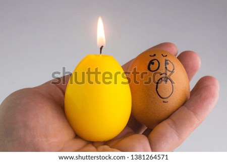special personality concept: positive yellow eggs-candle next to a surprised simple chicken eggs in a man's hand