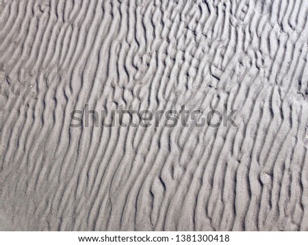Sandy beach with sea on background.Sand and wind pattern on dune surface.