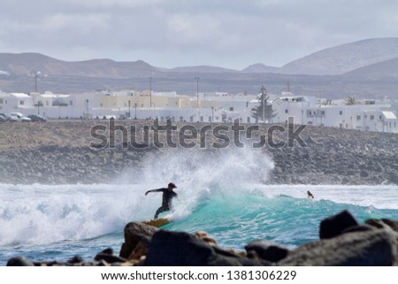 Panoramic picture with a body boarder and in the background volcanoes and the La Santa village in Lanzarote in the canary islands