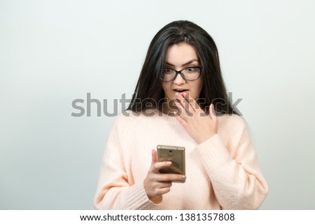 Young beautiful woman using mobile phone studio on white color background. Looking attentively at screen of cellphone, browsing web pages. 