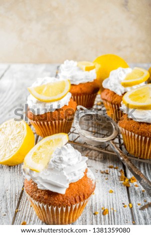 Homemade lemon cupcakes, sweet and sour baking pastry, with fresh lemon slices, wooden background copy space
