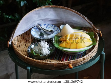 Thai desserts : sticky rice with ripe mango and coconut ball dessert in bamboo basket on dark background, Top view