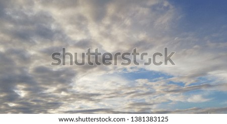 The battle of light and darkness. Light white clouds and dark clouds in the blue sky. Interesting unusual background