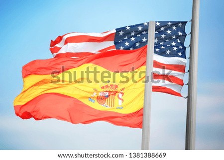 Flags of Spain and the USA against the background of the blue sky