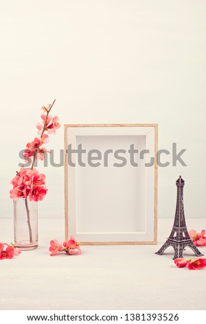 Mock up with empty picture frame, decorative Effel tower and pink tender spring flowers.