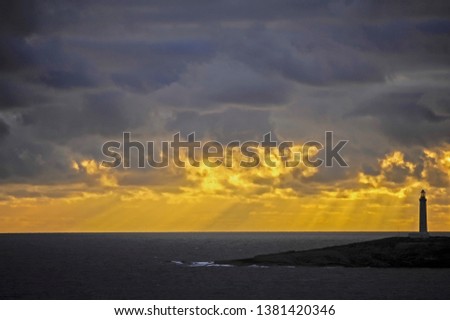 Stunning yellow and gray sunset, with natural light rays coming down to the ocean.
Sun is hidden behind very dark rain clouds, making the yellow rays more dramatic, all natural.