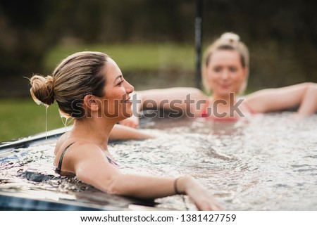 Mid adult woman relaxing in a hot tub with her friends. Royalty-Free Stock Photo #1381427759