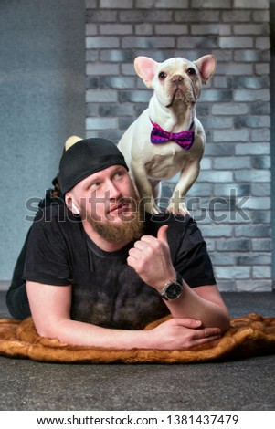 Hipster guy with his nice French Bulldog dogdressed in bow tie against brick wall on background. Pets love concept