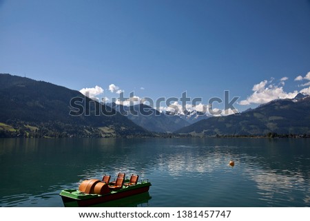 The lake at Zell am See in Austria pictured on a beautiful, calm and sunny June day with only a small boat and the reflected mountains on the water. A most beautiful spot for holidays.