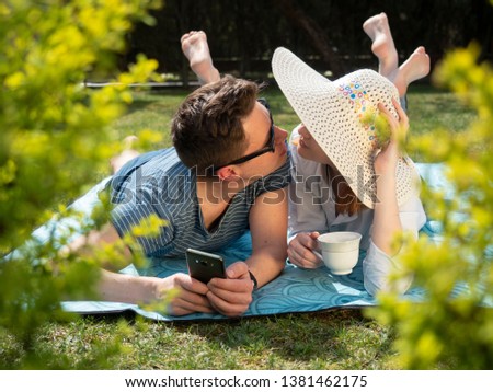 a pair of happy lovers resting on the grass with bare feet laughing and rejoicing